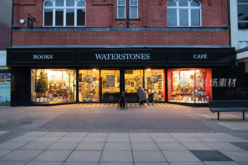 在英国西北部一条衰落的大街上，一位单身老人在英国水石书店关闭的分店外读着标牌。在COVID - 19封锁期间拍摄的。